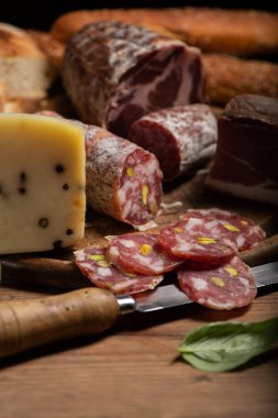 Jambonlu, salamlı, peynirli, ahşap bir tahtanın üzerinde ekmek kesme tahtası.