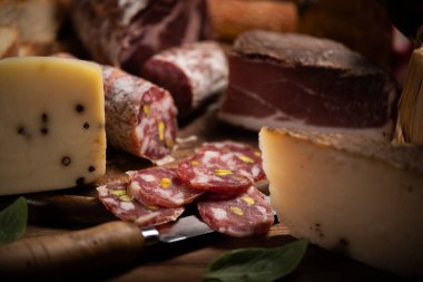 Jambonlu, salamlı, peynirli, ahşap bir tahtanın üzerinde ekmek kesme tahtası.