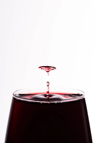 白の近いUに隔離されたガラスの中に落ちる赤ワインの液滴 — ストック写真