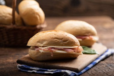 Two sandwiches with ham and cheese on wooden table close up