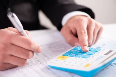 A finger adding up figures using a calculator close up