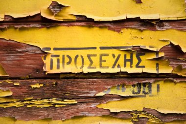 Eski sarı kabuklu ahşap bir yüzey ve Yunanca bir kelime.