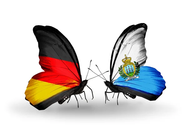 Två fjärilar med flaggor på vingarna som symbol för förbindelserna mellan Tyskland och san marino — Stockfoto