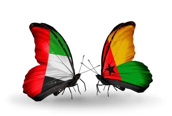 Zwei Schmetterlinge mit Flaggen auf Flügeln als Symbol der Beziehungen uae und Guinea Bissau — Stockfoto