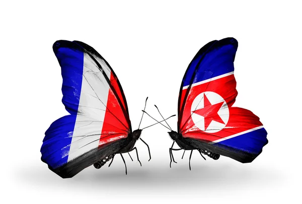 Två fjärilar med flaggor på vingarna som symbol för förbindelserna mellan Frankrike och Nordkorea — Stockfoto