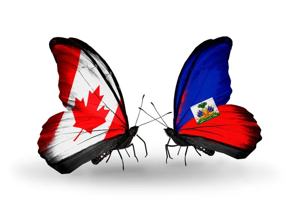 Dva motýli s příznaky na křídlech jako symbol vztahů, Kanady a na haiti — Stock fotografie