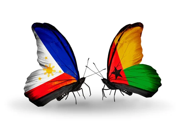 Twee vlinders met vlaggen op vleugels als symbool van betrekkingen Filippijnen en Guinee bissau — Stockfoto