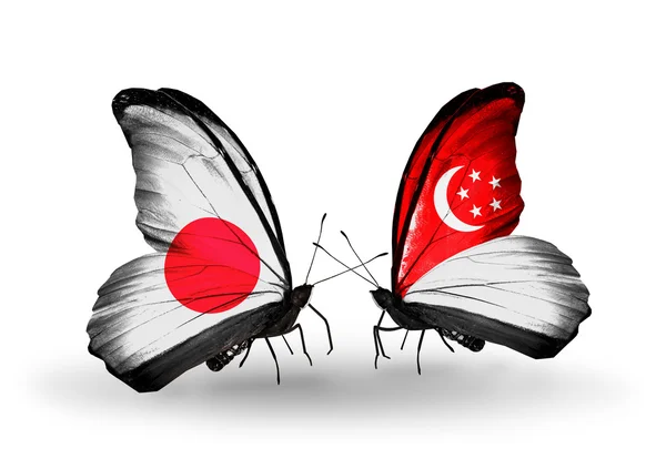 Dwa motyle z flagami na skrzydłach jako symbol stosunków japonia i Singapur — Zdjęcie stockowe