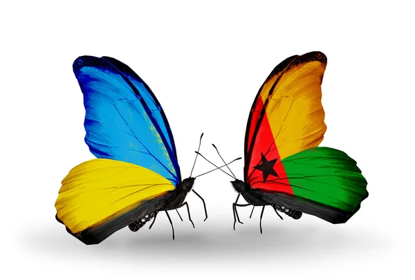 Due farfalle con bandiere sulle ali come simbolo delle relazioni Ucraina e Guinea Bissau — Foto Stock