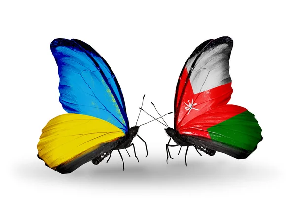 Dva motýli s příznaky na křídlech jako symbol vztahů, Ukrajina a Omán — Stock fotografie