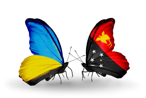 Zwei Schmetterlinge mit Flaggen auf Flügeln als Symbol der Beziehungen zwischen der Ukraine und Papua Neuguinea — Stockfoto