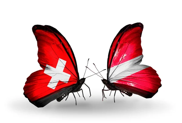 Two butterflies with flags of Switzerland and Latvia on wings — Stock Photo, Image