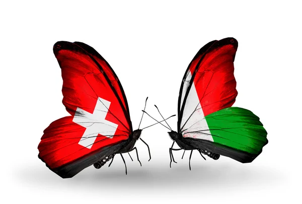 Dva motýli s vlajkami Švýcarska a Madagaskar na křídlech — Stock fotografie