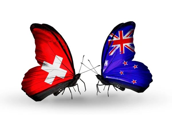 Zwei Schmetterlinge mit Fahnen der Schweiz und Neuseeland auf Flügeln — Stockfoto