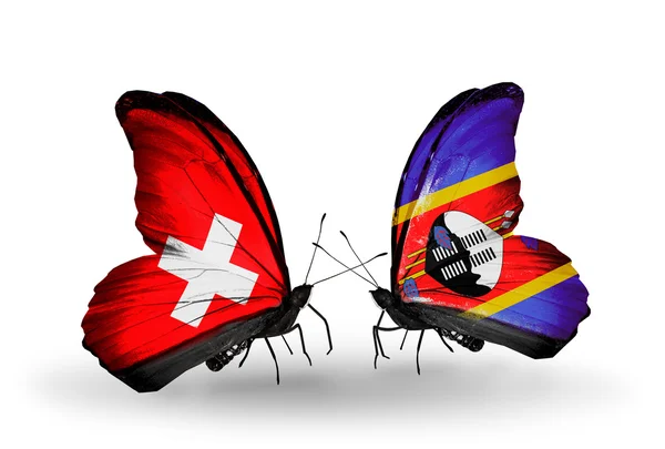 Dva motýli s vlajkami Švýcarska a Svazijska na křídlech — Stock fotografie
