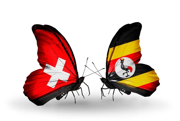 Två fjärilar med flaggor på vingarna som symbol för förbindelserna mellan Schweiz och uganda — Stockfoto