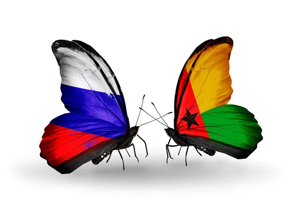 Deux papillons avec des drapeaux de la Russie et de la Guinée Bissau sur les ailes — Photo