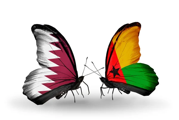 Vlinders met qatar en Guinee bissau vlaggen op vleugels — Stockfoto