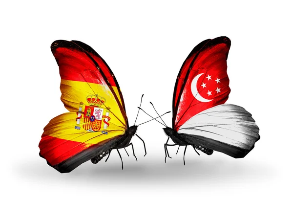 Butterflies with Spain and Singapore flags on wings — Stock Photo, Image