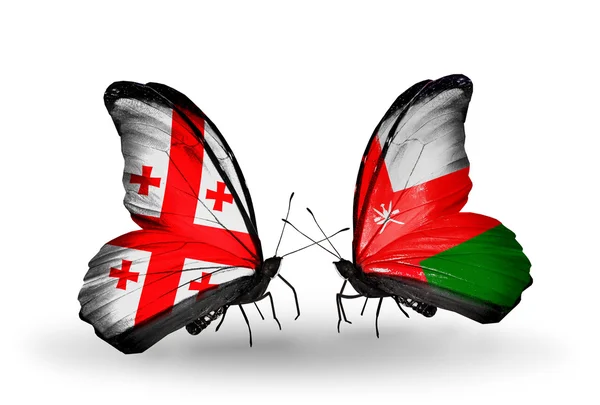 Schmetterlinge mit Georgien und omanischen Flaggen auf Flügeln — Stockfoto