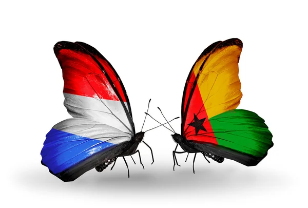 Farfalle con le bandiere del Lussemburgo e della Guinea Bissau sulle ali — Foto Stock