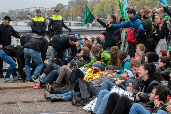 Protestocular, Hollanda 2019 'da Amsterdam' daki yok oluşun ardından Blauwebrug 'da iklim gösterisinde yerde yatıyorlar.