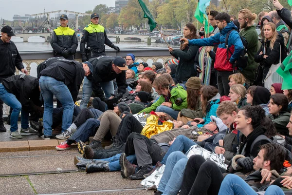 Protestocular, Hollanda 2019 'da Amsterdam' daki yok oluşun ardından Blauwebrug 'da iklim gösterisinde yerde yatıyorlar.