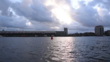 Amsterdam Merkez İstasyonu 'nun arka planında IJ ile Hollanda 2020