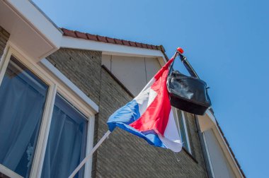 Hollanda 2018 'de Amsterdam' da bayraktaki okul çantası. Hollanda Okul Sınavlarını Geçme Geleneği.