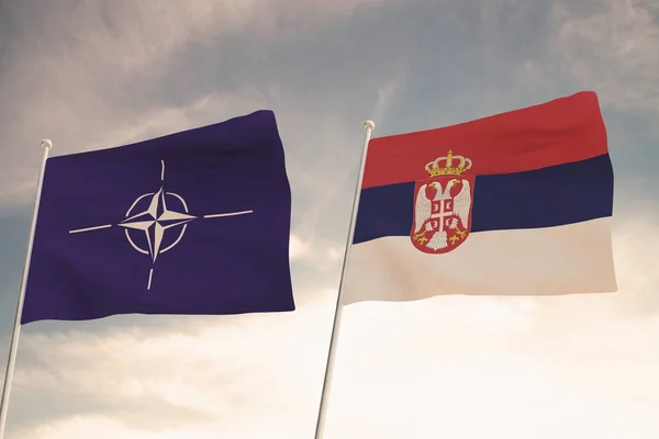 NATO ve SERBIA bayrakları bulutlu mavi gökyüzü arkaplanıyla dalgalanıyor.