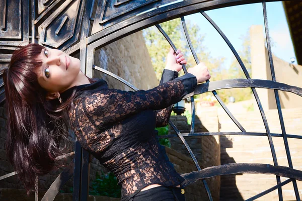 Schönes junges Mädchen posiert gegen Zaun — Stockfoto