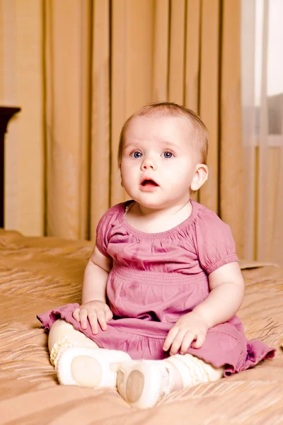 Lilla baby i röd klänning sammanträde — Stockfoto