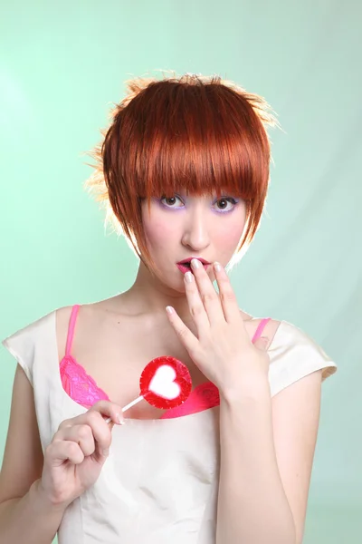 Red head girl with red lollipop with heart — Stock Photo, Image