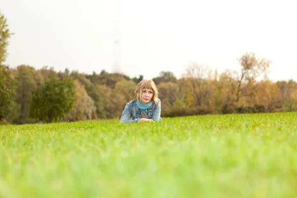 Молодая девушка лежит в парке на зелени — стоковое фото