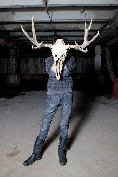 Man with a deer skull for a head in a dark basement — Stock Photo, Image