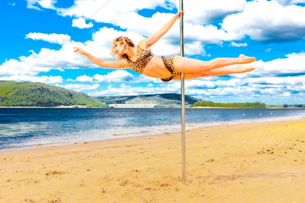 Chica hacer pole dance en un traje de baño en la playa fondo cielo mar y montañas —  Fotos de Stock