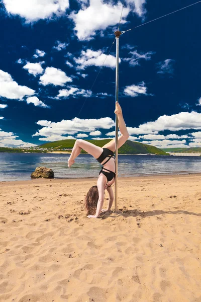 Kız olun kutup dans bir mayo plaj arka plan gökyüzü deniz ve dağlar