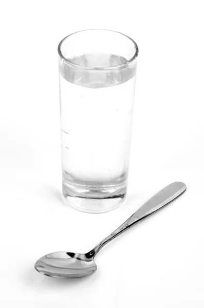 Glas water en lepel — Stockfoto