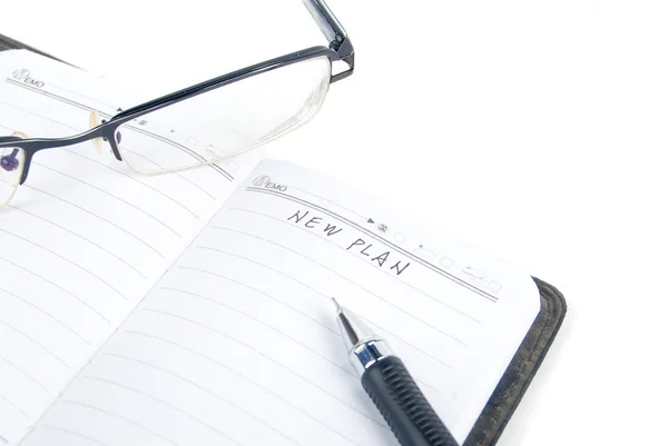 Bloco de notas e óculos sobre fundo branco — Fotografia de Stock