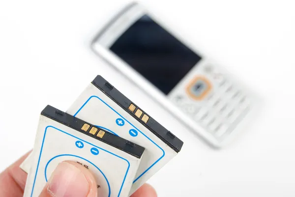 Batteri och telefon på vit bakgrund — Stockfoto