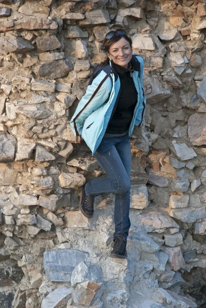 Woman standing by a stone wall — Stock Photo, Image