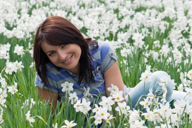 Nergis arasında oturan kadın gülümsüyor