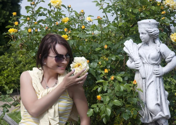 Young woman with a yellow roses in the garden — Stock Photo, Image