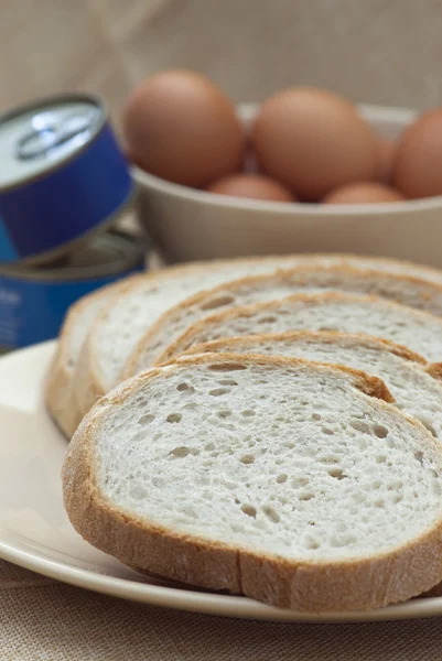 Sliced bread, canned food and eggs in a bowl. — Stock Photo, Image
