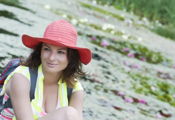 Beautiful woman in a hat and lake with water lilies — Stock Photo, Image