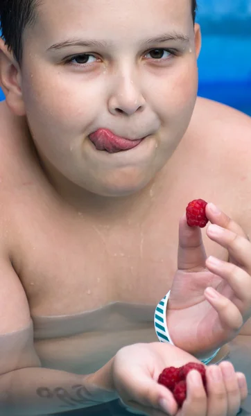 Chico come frambuesas en la piscina — Foto de Stock