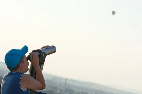 Jonge jongen kijken de vliegende baloon door telescoop. — Stockfoto