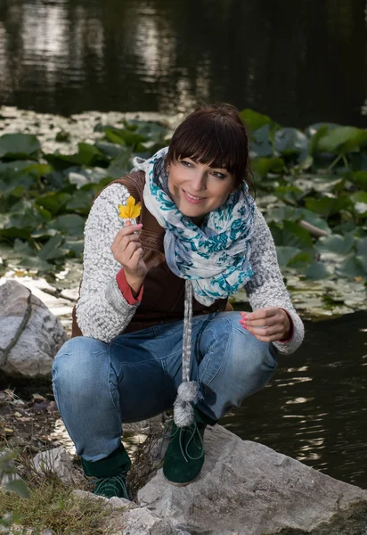 Beautiful woman holding yellow leaf in hand — Stock Photo, Image