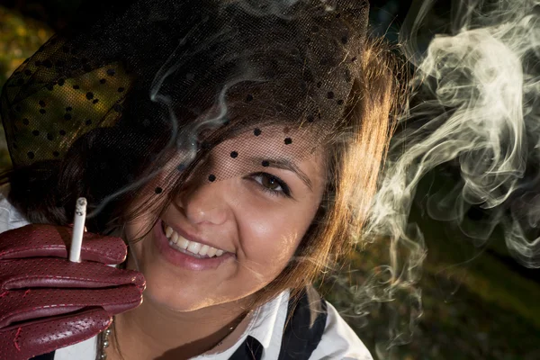 Young smiling woman smokes a cigarette — Stock Photo, Image