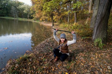 genç kadın bir tahta sopa ile eğlenceli bir ormanda sonbahar yapar